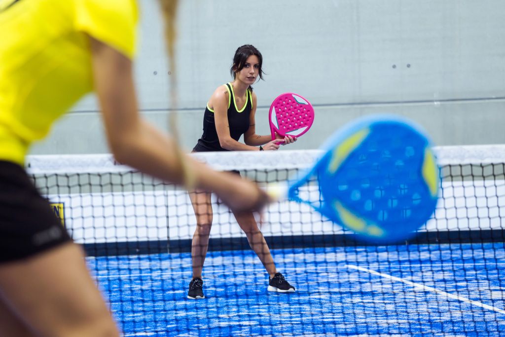 Foto von zwei jungen Frauen, die Paddle-Tennis spielen.